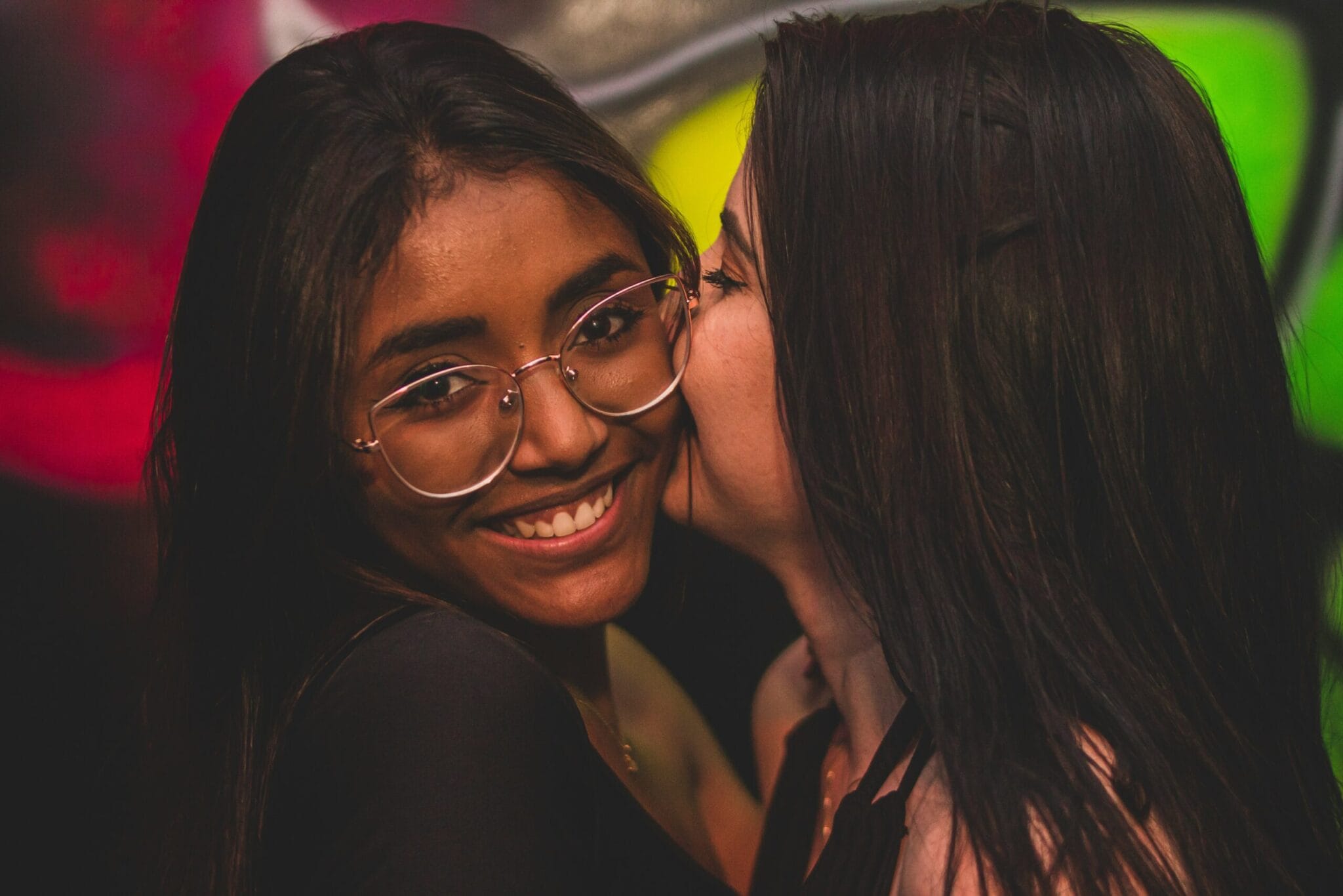 Two international solo traveler enjoying Berlin nightlife on a pub crawl, smiling and posing for a photo during the bar hopping tour