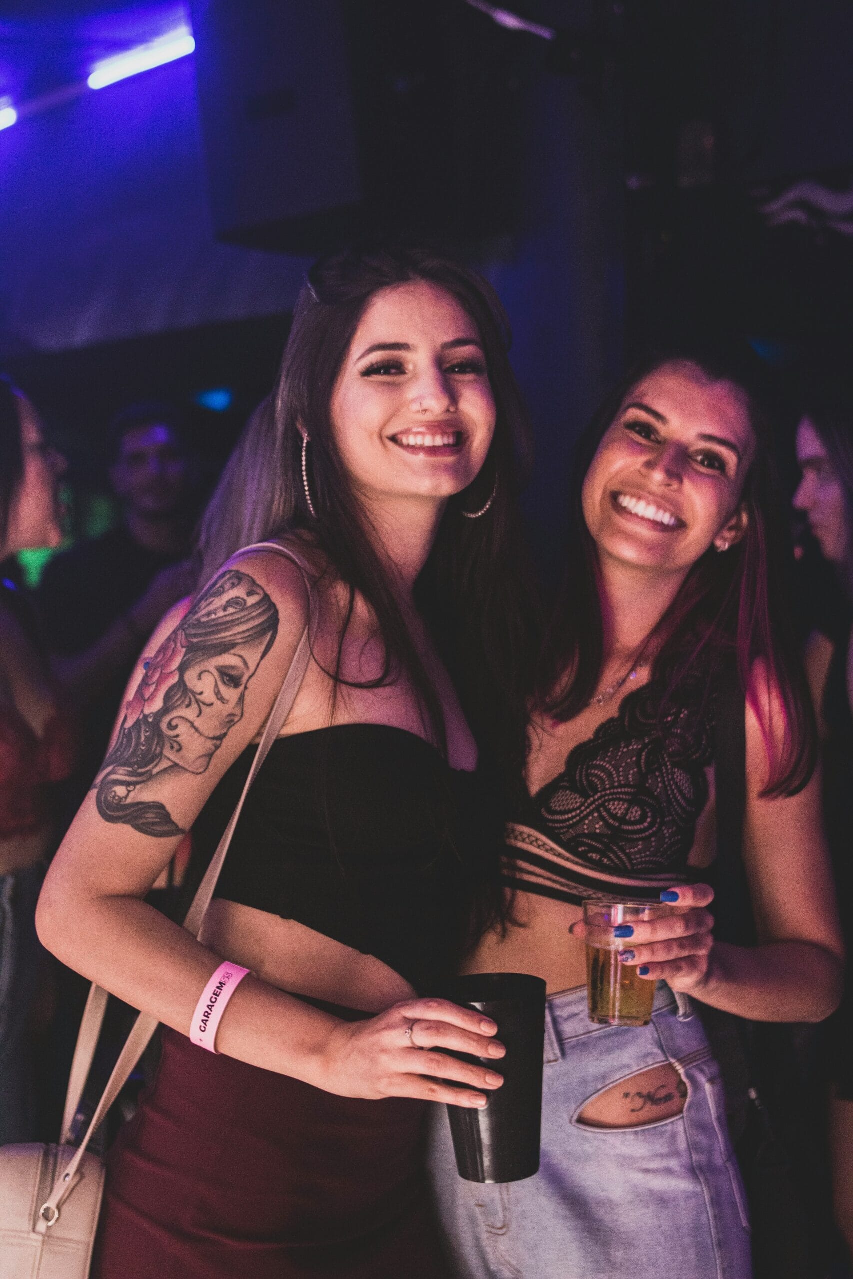 Two beautiful party girls enjoying drinks during a Berlin pub crawl, smiling and socializing in the bar