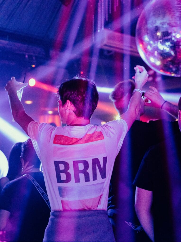 Dancing guest at Berlin pub crawl nightclub, wearing BRN shirt and enjoying party atmosphere